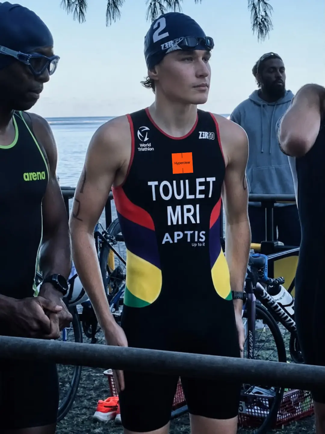 Young triathlete Adrien Toulet standing in competition tri-suit and swim cap, representing the Raise for a Child Athlete Development pathway.