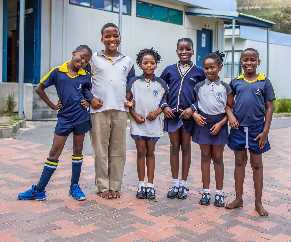A group of young South African school learners smiling outside their classroom, representing the Raise for a Child and Bright Start educational partnership program.
